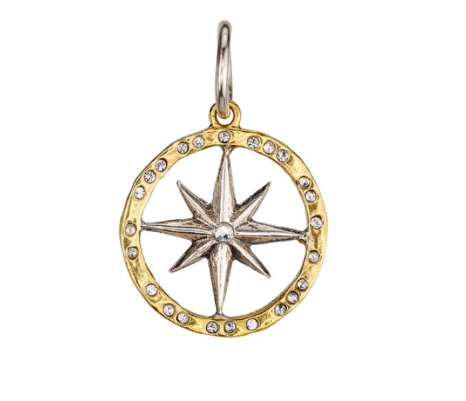 The Wonderer Compass Charm by Waxing Poetic is a gold circular charm with an eight-pointed silver star at the center, encircled by a crystal-studded brass band set with small clear gemstones.