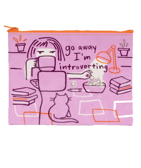 The Blue Q Go Away Introverting Pouch is pink, made from recycled material, and shows a cartoon person with a cat at a desk. “Go away I’m introverting” appears on the pouch—perfect for any cat lover.