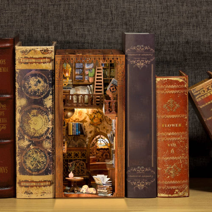 A bookshelf displays vintage books; one opens to reveal the Hands Craft DIY Book Nook Kit: Eternal Bookstore with Dust Cover, featuring miniature bookshelves, stairs, and warm lighting—a perfect gift for book lovers.