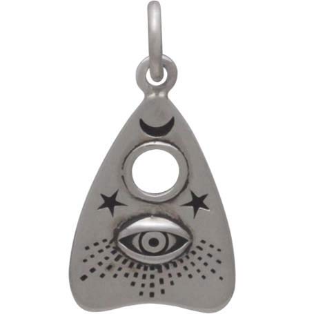 The Silver Ouija Planchette Charm with All Seeing Eye from Nina Designs captures the mystical allure of a seance with its detailed design, featuring an eye, crescent moon, two stars, and dotted patterns reminiscent of an Ouija board's enigmatic essence.