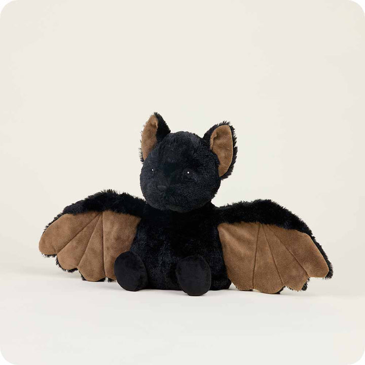 A Bat Warmie plush toy from Warmies, featuring black fur and brown wings, is displayed on a neutral background. Its large ears stand upright, and its small eyes gleam.