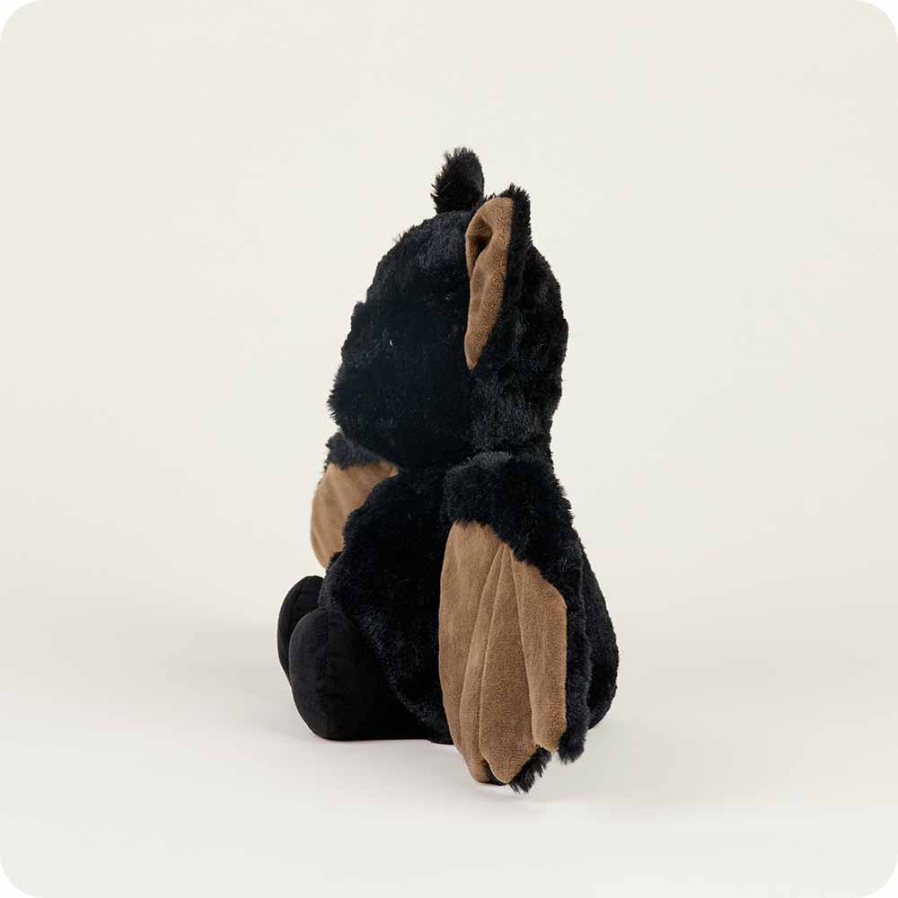 The Bat Warmie plush toy from Warmies, featuring black fur and brown wings, is positioned sideways against a light background.