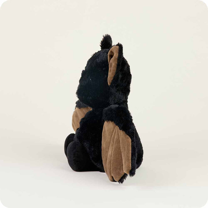 The Bat Warmie plush toy from Warmies, featuring black fur and brown wings, is positioned sideways against a light background.