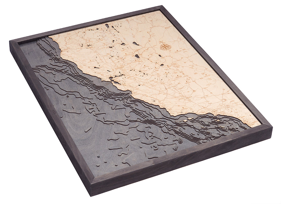 The WoodChart California Coast 24.5" x 31" Grey Frame is a layered wooden map with carved land and ocean contours, showing roads, topography, and depth lines in contrasting woods.