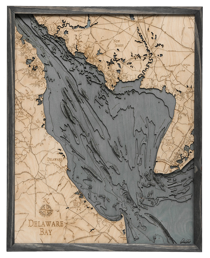 The WoodChart Deleware Bay 24.5 x 31 Grey Frame is a wooden, laser-cut map showing water depths and coastal features of Delaware Bay and nearby regions in Delaware and New Jersey, highlighted in varying shades and set in a grey frame.