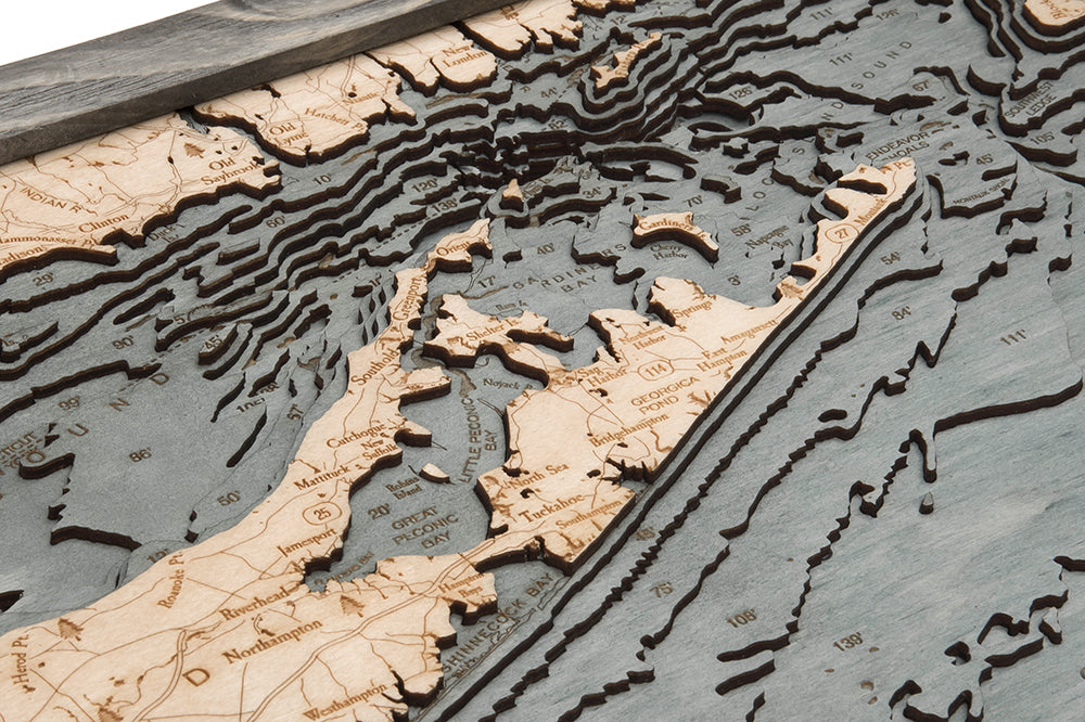 A close-up of the WoodChart Long Island Sound 13.5" x 31" map in a grey frame, featuring detailed layered wood topography, engraved place names, and surrounding waters of Long Island, New York.