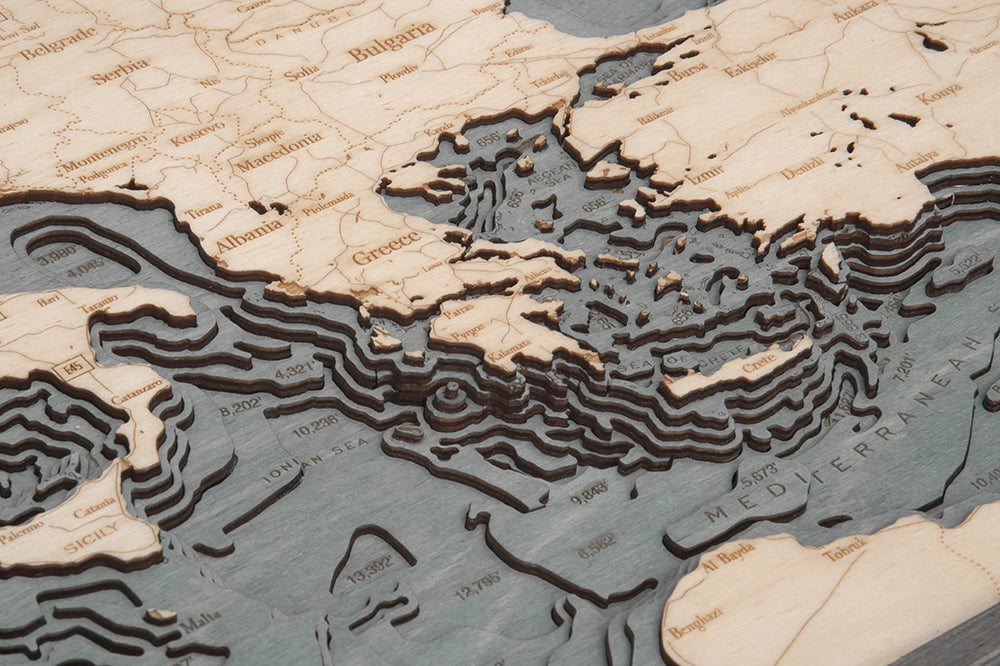 The WoodChart Mediterranean Sea 13.5" x 31" Grey Frame map features layered wood cutouts of the Mediterranean region, including Greece and Italy, showcasing detailed underwater terrain in a stylish grey-framed display.