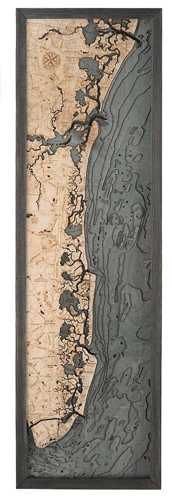 The WoodChart NJ South Shore 13.5" x 43" map features a vertical, framed wood-cut design with beige land on the left and layered blue-gray ocean on the right, highlighting coastal contours in a stylish grey frame.