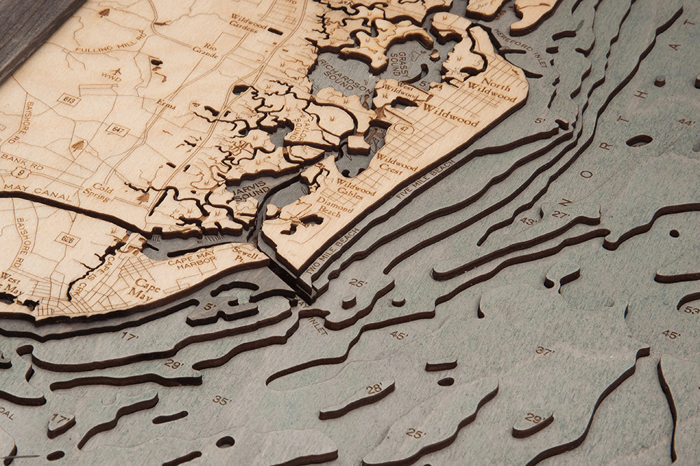The WoodChart NJ South Shore 13.5" x 43" Grey Frame displays the New Jersey shoreline near Cape May, with engraved land features, ocean depths, and landmarks like Wildwood and Cape May Canal.