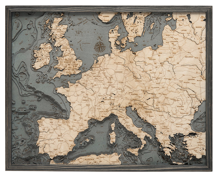 The WoodChart Western Europe Chart (24.5" x 31") features carved country borders, cities, and bodies of water with raised details and a decorative compass rose, all framed in an elegant grey border.