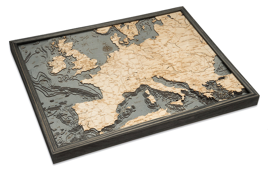 The WoodChart Western Europe Chart (24.5" x 31") features a framed, layered wooden map showing countries, borders, and topography in 3D detail within a grey frame, displayed at an angle on a white background.