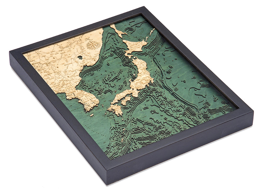 The WoodChart Japan Korea 16" x 20" Black Frame is a framed 3D topographic map of Japan and neighboring regions, with beige land, green ocean, and detailed elevation and depth contours.