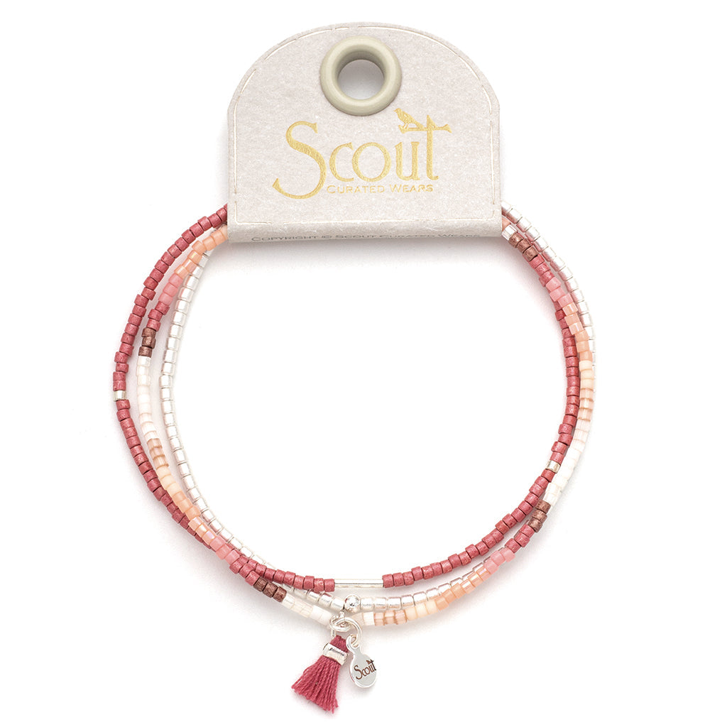 The Blush Multi Silver Miyuki Bracelet Trio from Scout Jewelry is a beaded bracelet featuring pink and peach tones, crafted with Miyuki Delica beads. It includes a small silver charm and tassel, designed for seamless stacking with other pieces and stretches to fit comfortably on the wrist. It's displayed on a card labeled "Scout Curated Wears.