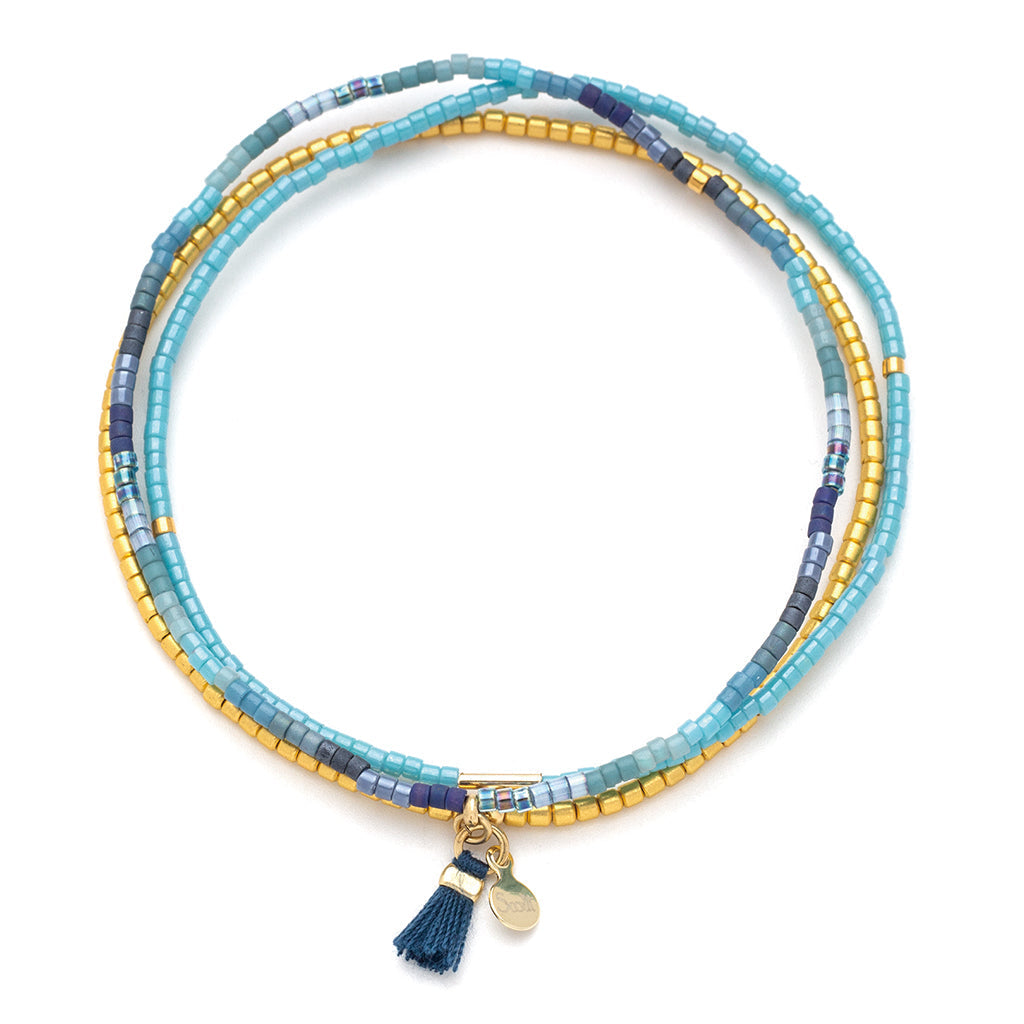 The Cobalt Multi Gold Miyuki Bracelet Trio from Scout Jewelry features a striking design with blue, gold, and purple Miyuki Delica beads. It is adorned with a small navy tassel and a round 14K gold charm. This bracelet is ideal for stacking with other pieces to craft a distinctive look.