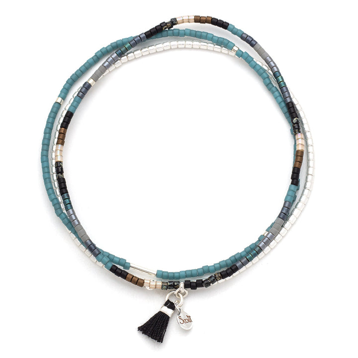 Introducing the Black Multi Silver Miyuki Bracelet Trio from Scout Jewelry. This stunning bracelet set is crafted with Miyuki Delica beads in shades of blue, black, and silver. Each piece features a small Sterling Silver-dipped charm and a black tassel pendant, adding a touch of elegance to any ensemble.