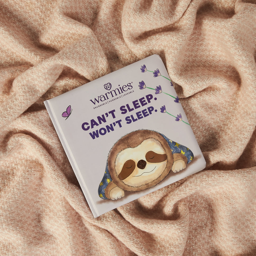 The children's book "Can’t Sleep Won’t Sleep" by Warmies shows a sleeping sloth in Lavender Land with butterflies. It's part of the Warmies Books collection and rests on a cozy beige blanket like a warm hug.