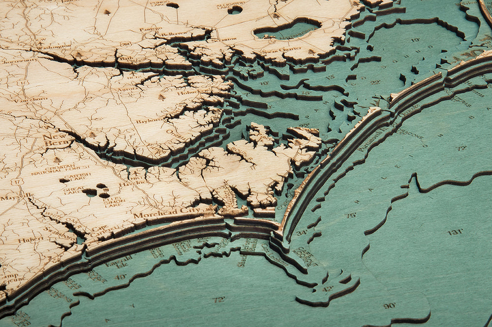 Close-up of the WoodChart North Carolina Coast 24.5" x 31" Black Frame, featuring detailed topography and water depth contours of the eastern U.S. coast, including labeled areas like New Bern and Morehead City.