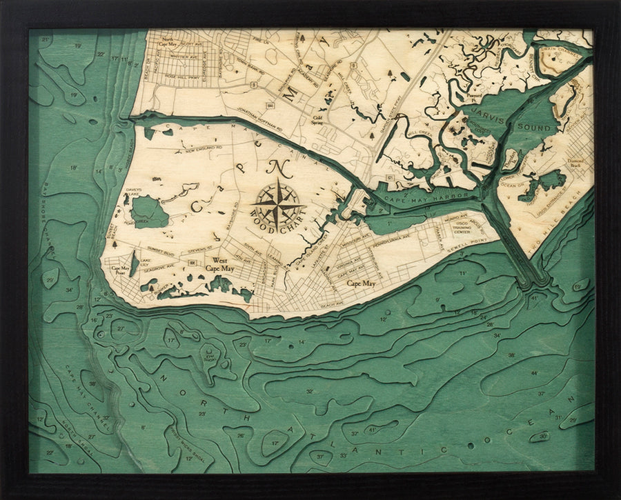 The WoodChart Cape May NJ 16" x 20" Black Frame is a carved wooden map with natural wood land, green water, labeled roads and waterways, and a compass rose.