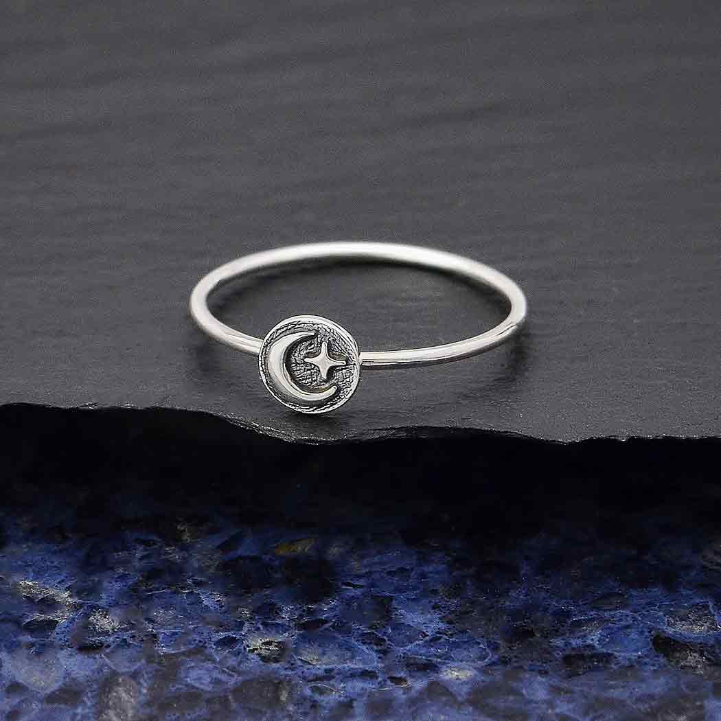 The s6 Raised Moon and Star Stacking ring by Nina Designs showcases a delicate crescent moon and star design on a textured sterling silver surface.