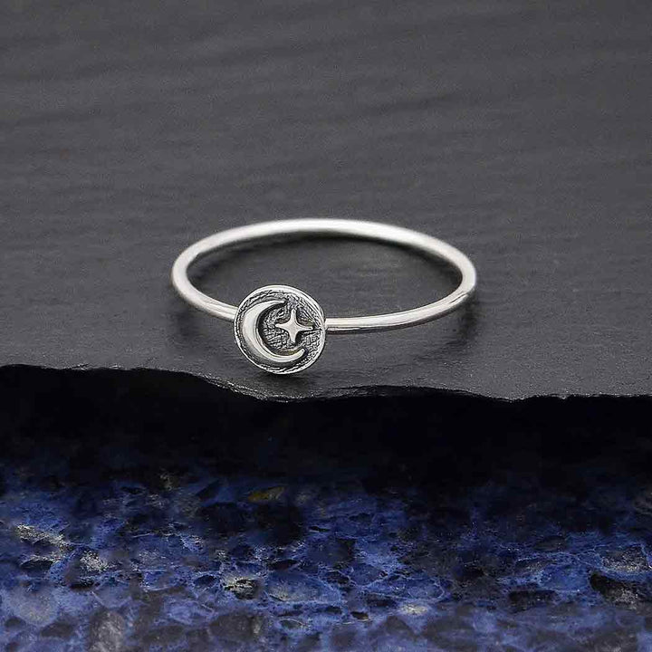 The s6 Raised Moon and Star Stacking ring by Nina Designs showcases a delicate crescent moon and star design on a textured sterling silver surface.