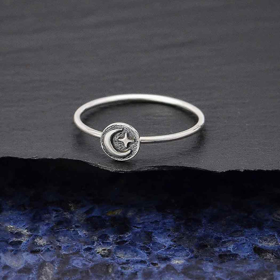 The s6 Raised Moon and Star Stacking ring by Nina Designs showcases a delicate crescent moon and star design on a textured sterling silver surface.