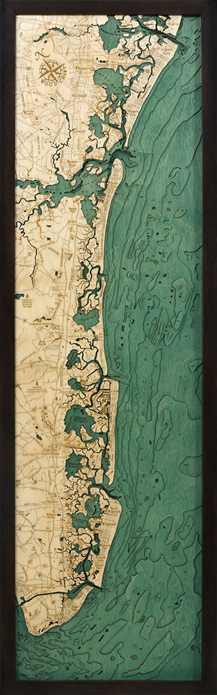 The WoodChart NJ South Shore 13.5" x 43" Black Frame features a vertical, framed wooden map with beige land marked with roads and towns, and green-shaded ocean and waterways, all intricately cut to show the coastal region.