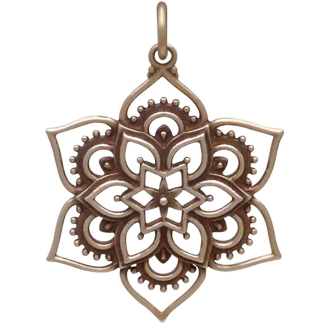 The Bronze Openwork Lotus Mandala Pendant by Nina Designs features a symmetrical six-petal flower with intricate patterns, crafted from Italian bronze alloy and includes a loop at the top for easy attachment to a chain.