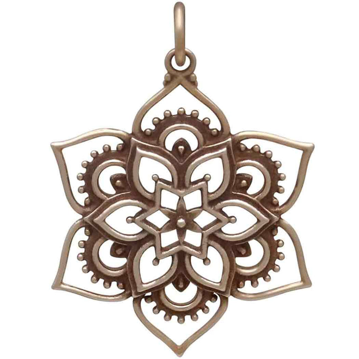 The Bronze Openwork Lotus Mandala Pendant by Nina Designs features a symmetrical six-petal flower with intricate patterns, crafted from Italian bronze alloy and includes a loop at the top for easy attachment to a chain.