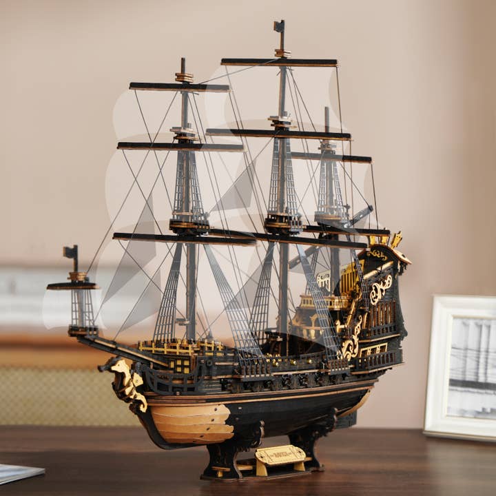 The Hands Craft DIY The Seahorse Barque Ship is a detailed wooden model of a historic three-masted vessel with intricate gold accents, perfect for display indoors on a table.