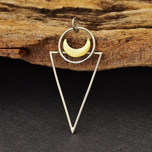 The Sterling Silver Triangle Pendant with Bronze Moon by Nina Designs features a yellow bronze crescent moon inside a circular frame with a soldered jump ring, all within a sterling silver triangle, shown on a textured wooden background.