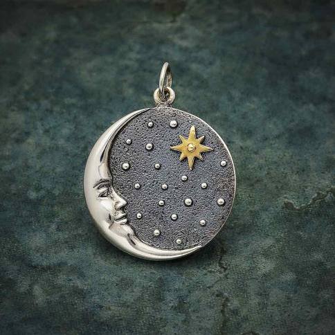 The Silver Crescent Moon Face Pendant with Bronze Star by Nina Designs features a silver crescent moon with a smiling expression set against a starry, dark textured background. A prominent bronze star is positioned near the center, and the pendant is elegantly displayed on a mottled dark green surface.