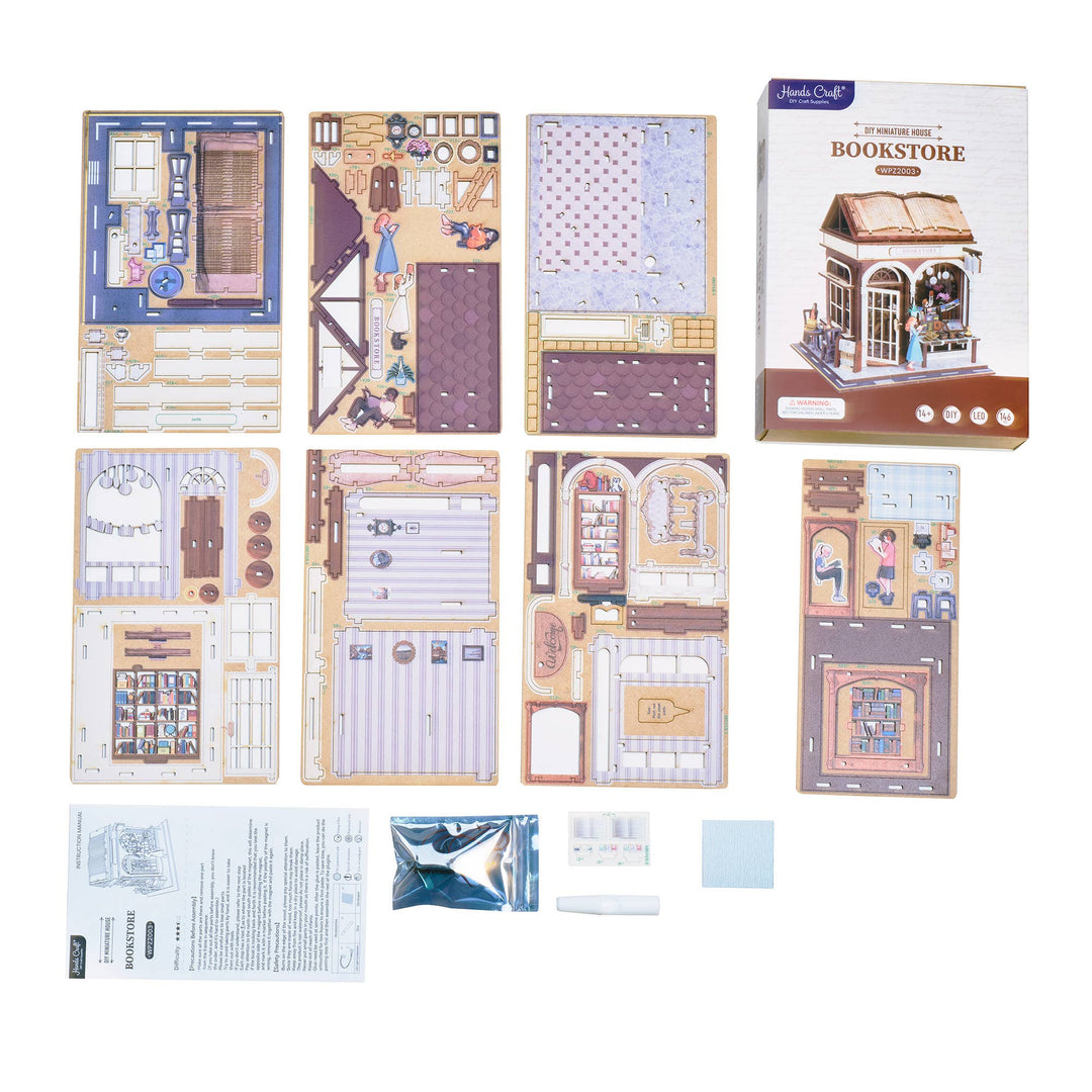 Flat lay of the Hands Craft DIY Miniature House Kit: Bookstore, featuring laser-cut wood sheets, small parts, tools, instruction manual, and product box displaying a cozy bookstore book nook model.