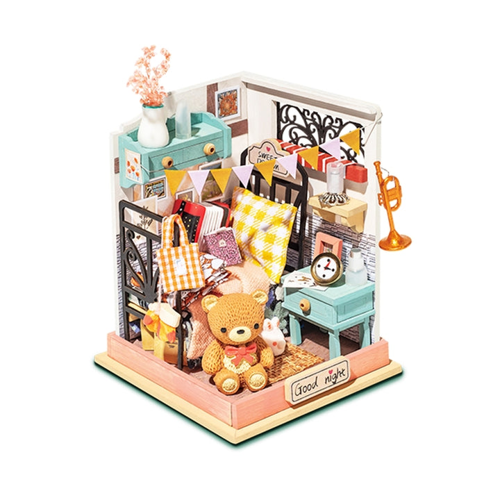 A detailed crafting project, the Hands Craft Bedroom DIY Micro Miniature Kit features a cozy bedroom scene with a teddy bear, small furniture, books, and decorative items like bunting flags, a small trumpet, and flowers. The bed has yellow checkered bedding with a "Good night" sign placed in front—truly a unique hands-on gift.