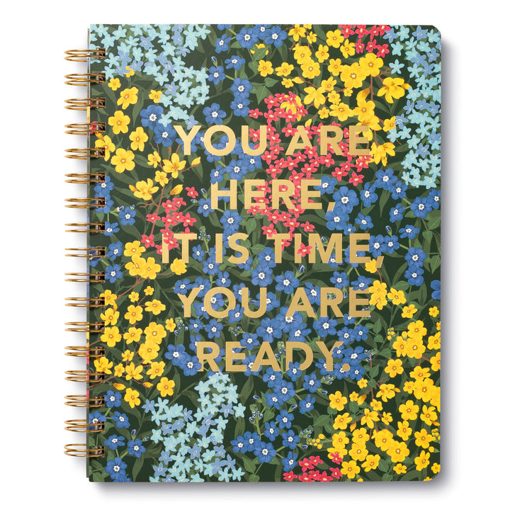 The "You are here It is time Spiral Notebook" by Compendium features a spiral-bound design with a vibrant floral pattern showcasing yellow, red, and blue flowers. It's an ideal choice for bullet journaling with its college-ruled lined pages that provide plenty of space for your creative ideas. The cover is adorned with the motivational text: "YOU ARE HERE. IT IS TIME. YOU ARE READY.