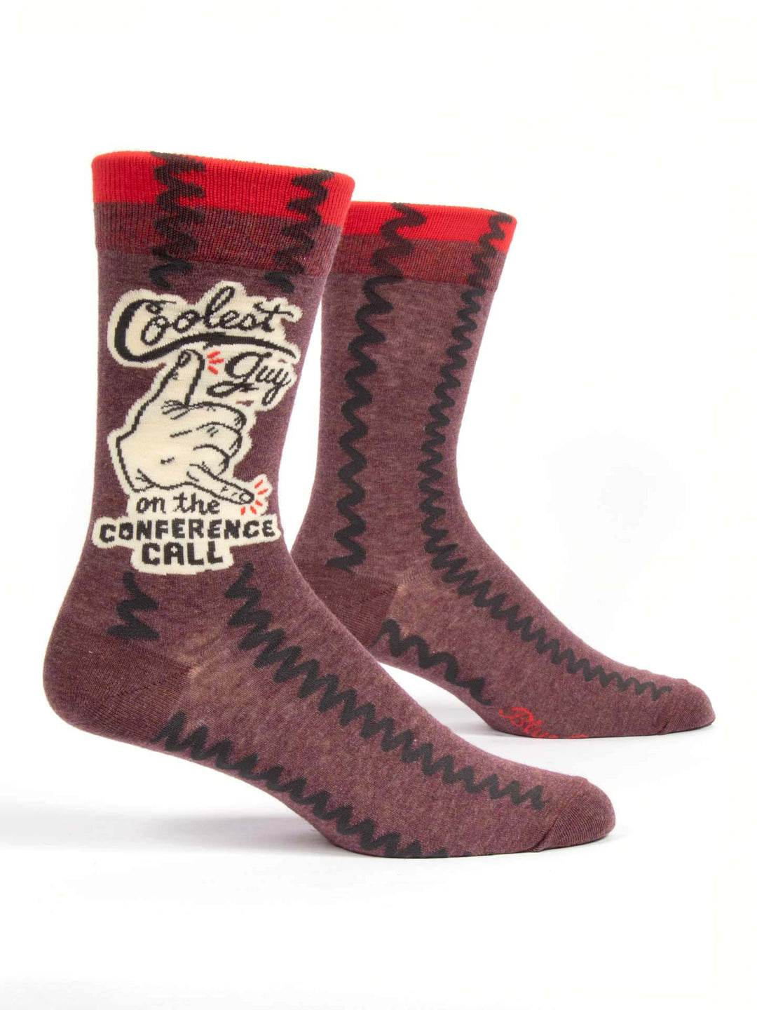 The Coolest Guy socks by Blue Q are designed in a retro style, boasting a brown base with red accents. They are perfect for the workplace, featuring one sock with the text "Coolest guy on the conference call" next to an illustration of a hand giving a thumbs-up. These socks also showcase a zigzag pattern running down the sides and fit men's shoe sizes 7-12.