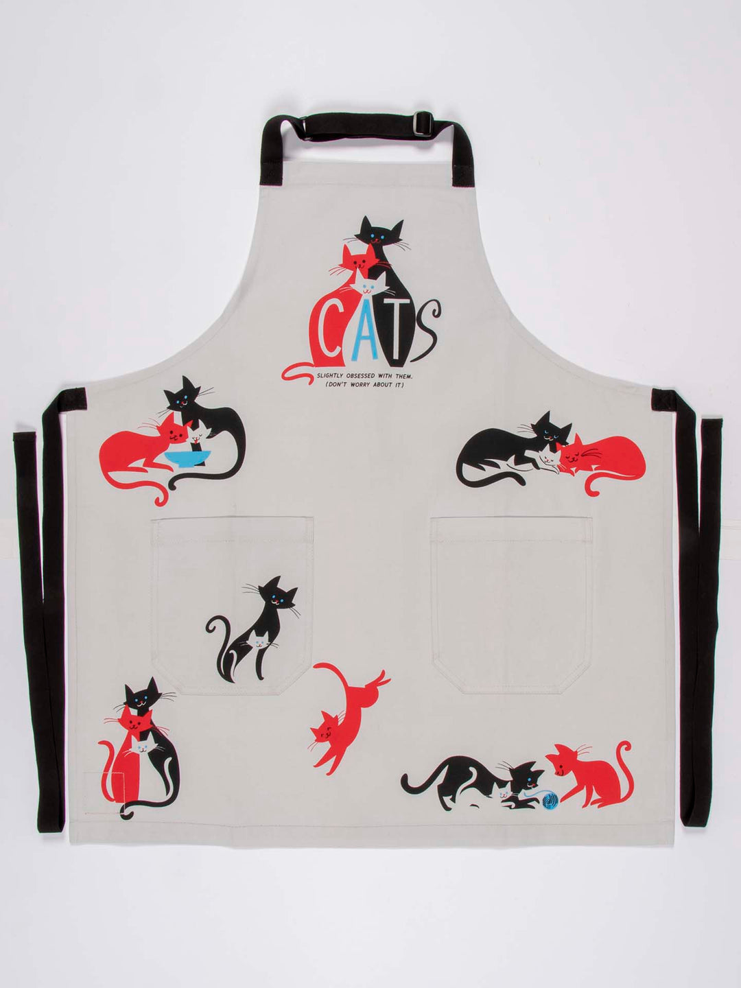 The Cats Apron by Blue Q features playful black and red cat illustrations across the pockets and chest, crafted from heavy cotton twill. The word "CATS" is prominently displayed on the chest with whimsical lettering, complemented by easy-adjust neck straps for a comfortable fit.