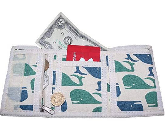 The Tri Fold Wallet Whale by Bungalow 360, made from sturdy cotton canvas and adorned with distinctive whale patterns, is displayed open to showcase a $2 bill, several coins, and a red card.