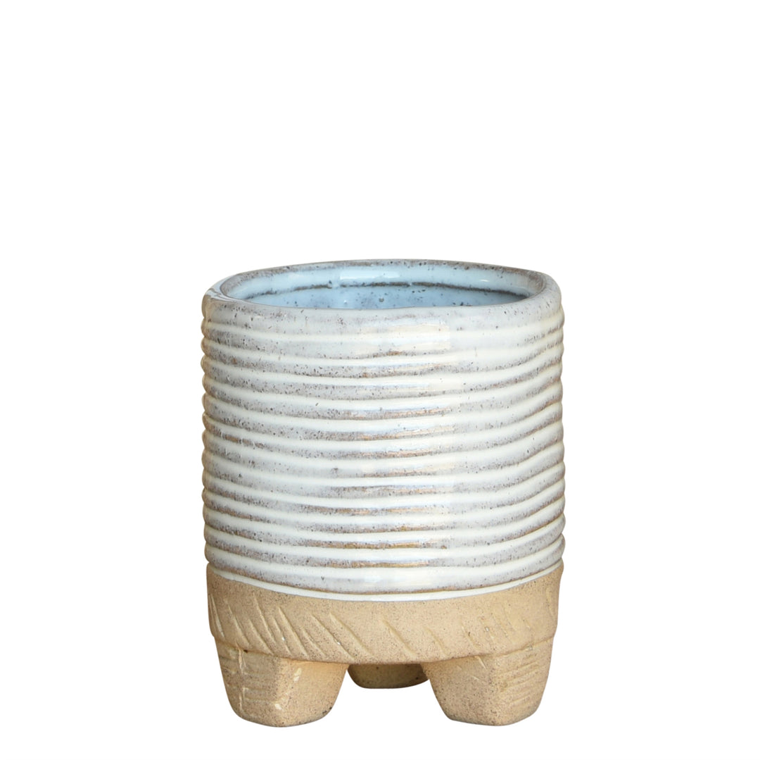 Introducing the Horizontal Stripe Cachepot by HomArt: This compact, cylindrical ceramic planter showcases a ribbed light blue top and a smooth beige base, supported by three short legs. Perfect for indoor gardening, this hand-sculpted stoneware piece effortlessly combines rustic charm with minimalist design against a plain white background.