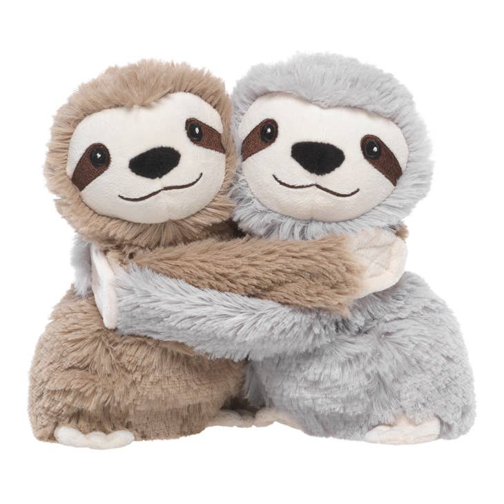 Two Sloth Hugs Warmies from the Warmies brand, one brown and one gray, are sitting and embracing each other with smiles on their faces. The soft, fuzzy texture of their fur gives them a cuddly appearance, and they seem to be in a friendly, affectionate gesture. These heatable characters are filled with real dried French lavender.