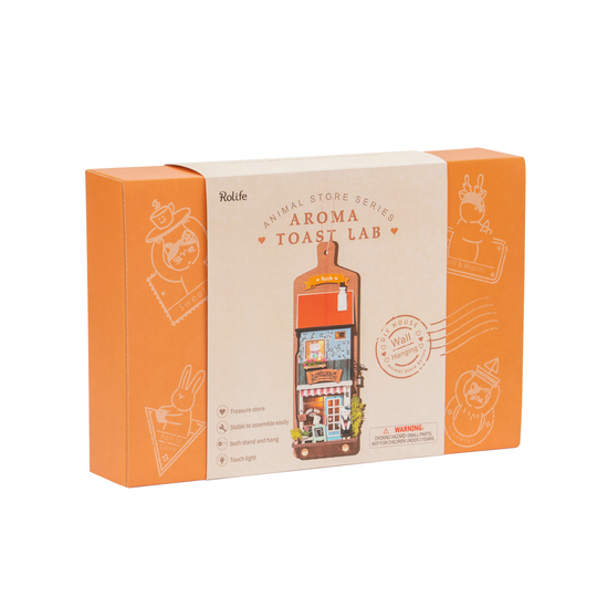 The "DIY Miniature Wall Hanging Kit: Aroma Toast Lab" by Hands Craft comes in orange packaging with real lighting. The box highlights a light-up miniature store, cute animal graphics, and serves as a charming DIY wall display while including assembly warnings.