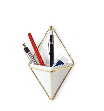 The White Diamond Small Wall Vase by Umbra, featuring a white, triangular design with a gold frame, stylishly mimics an indoor mini wall garden. It neatly holds two pens, a red pencil, a ruler, and a small notebook.