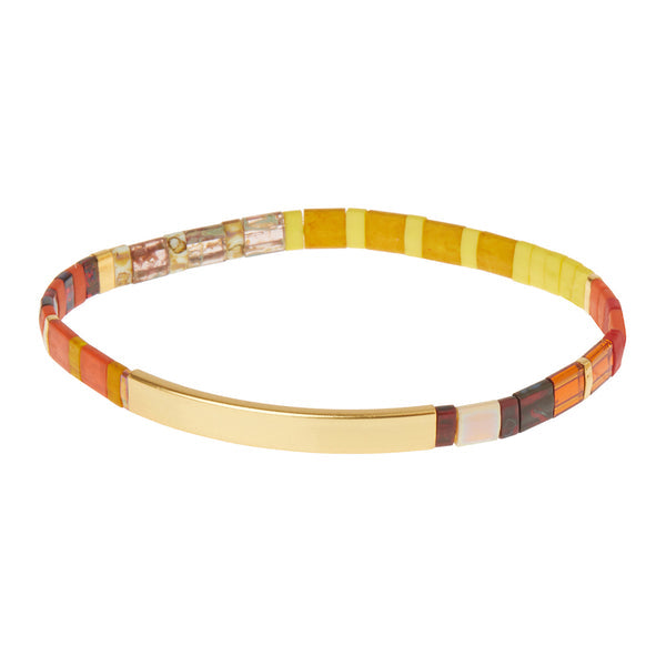 The Miyuki Be Fierce Sunset Gold bracelet by Scout Jewelry showcases multicolored tones of yellow, red, orange, and brown with a smooth 14K gold dipped bar at its center.