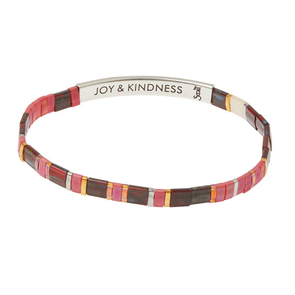 The Miyuki Joy and Kindness Mulberry Silver bracelet by Scout Jewelry features slim red, pink, brown, and gold beads with a sterling silver-dipped bar engraved "JOY & KINDNESS," inspired by Japanese Miyuki glass designs.
