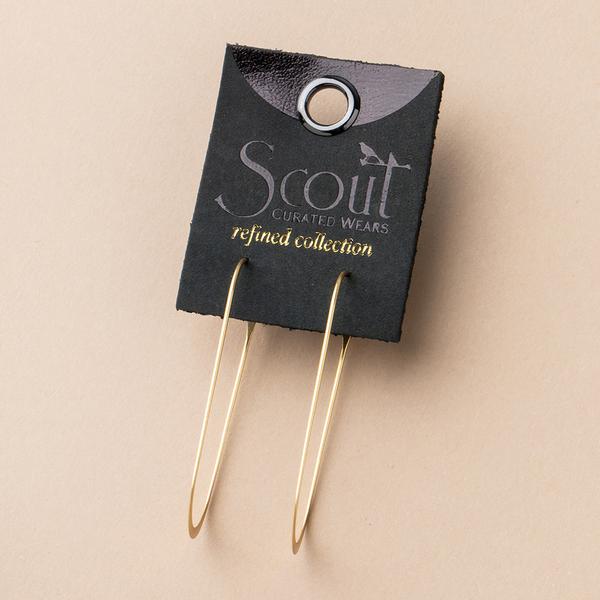 A pair of stylish "Cosmic Oval Gold" hoop earrings from Scout Jewelry, made from 18K Gold Vermeil and designed to be hypoallergenic, nickel, and cadmium free, is attached to a black card labeled "Scout Curated Wears refined collection," featuring a decorative hole at the top against a beige background.