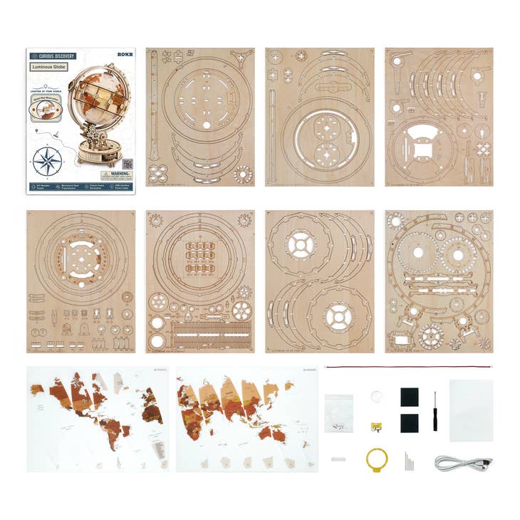 The Hands Craft DIY Wooden Puzzle: Luminous Globe laid out on a white surface. This 3D wooden puzzle kit includes laser-cut wooden sheets with various shapes, assembly instructions, world map decals, small hardware pieces, and a USB cable. When assembled, it forms a luminous globe that doubles as a night light.