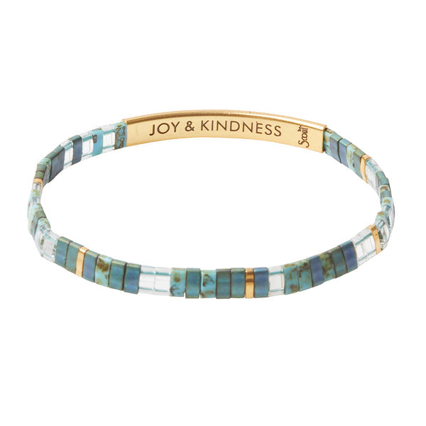 The Miyuki Joy and Kindness Marine Gold bracelet by Scout Jewelry is meticulously crafted using sophisticated Japanese glass Miyuki beads in various shades of blue, complemented by elegant gold accents. It includes a 14K Gold dipped bar engraved with the inspiring message "JOY & KINDNESS.