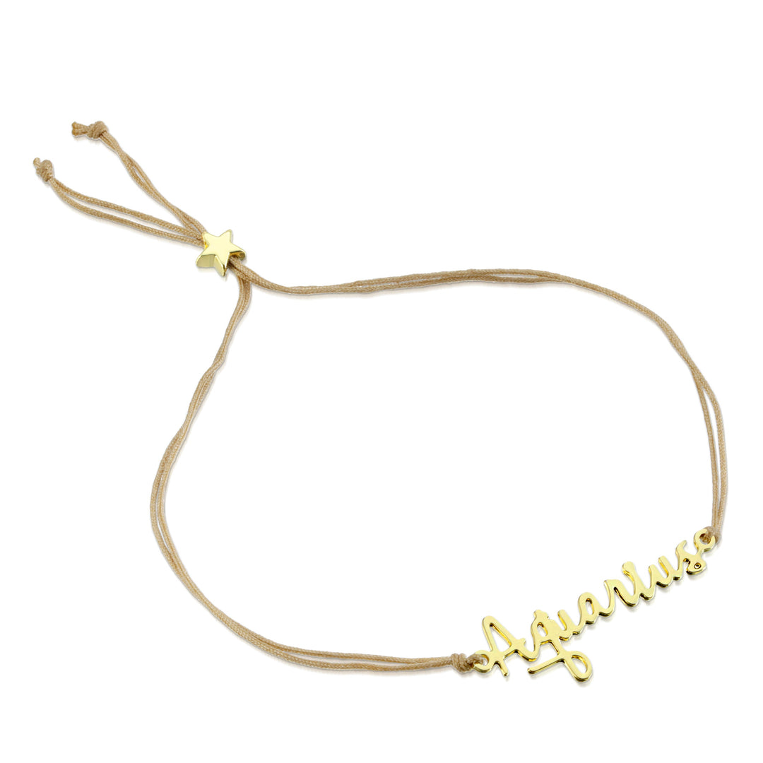 The LuckyFeather Zodiac Bracelet Aquarius features a beige cord with a nickel-free, 14k gold-dipped "Aquarius" charm in cursive, an adjustable sliding knot, and a small star accent.