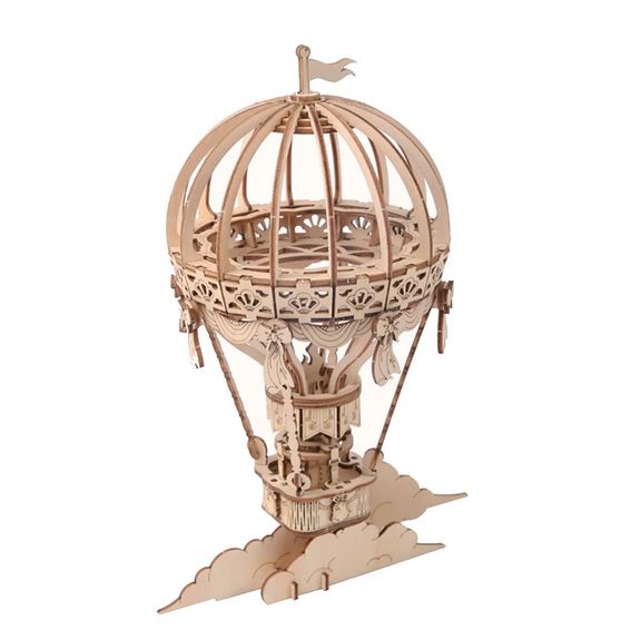 The Hands Craft 3D Wooden Puzzle Hot Air Balloon is a detailed model featuring intricate patterns and designs in a modern vintage style. It showcases an open frame cage-like structure on the top, with a basket below, all supported by thin wooden rods. The base includes a decorative cloud motif, making it perfect as a DIY 3D wooden puzzle.