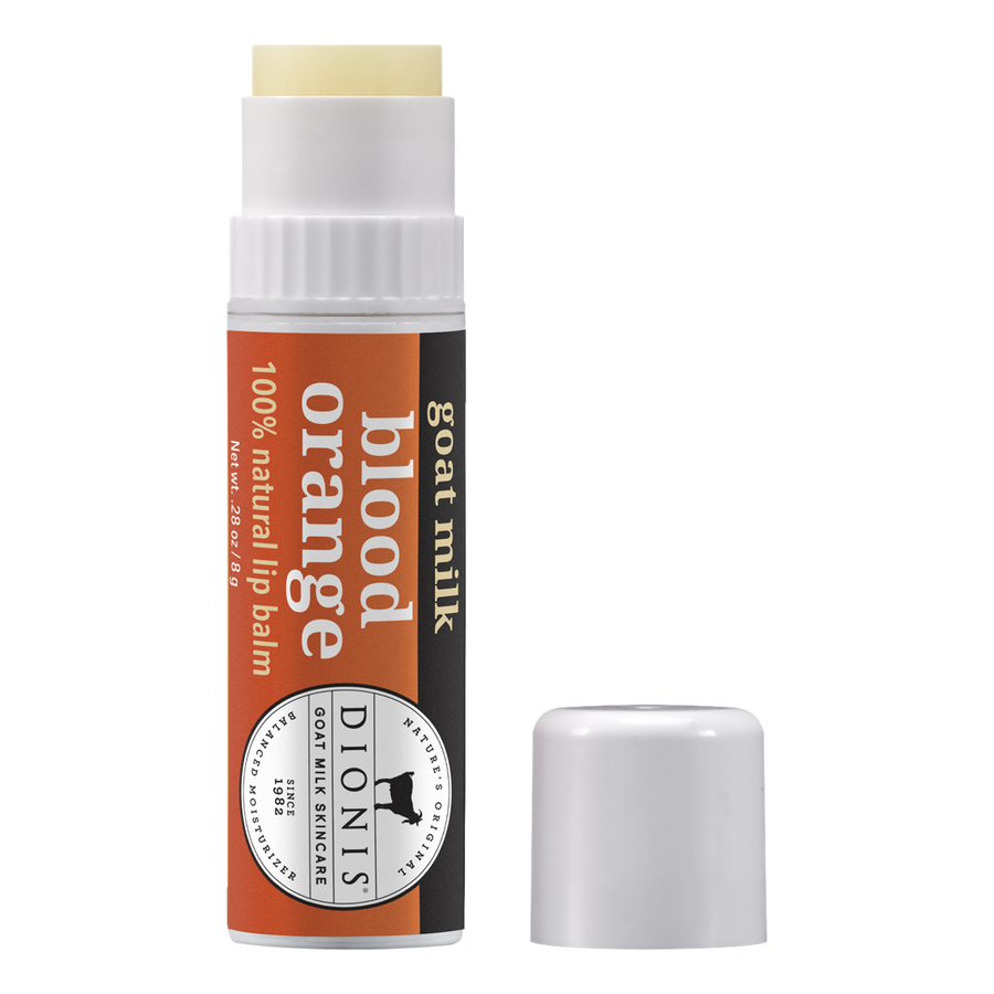 A tube of Dionis Lip Balm Blood Orange is displayed with its cap removed. The packaging is white with an orange label that showcases the product name and highlights its 100% natural formulation. The paraben-free cap lies beside the open tube.