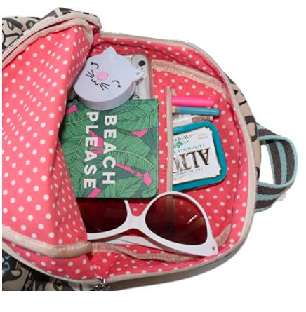 Open the Backpack Cat by Bungalow 360, made from natural cotton canvas with a polka-dotted pink interior containing a phone with a cat face case, a notebook titled "Beach Please," sunglasses, a pack of mints, a pencil, and lip balm.